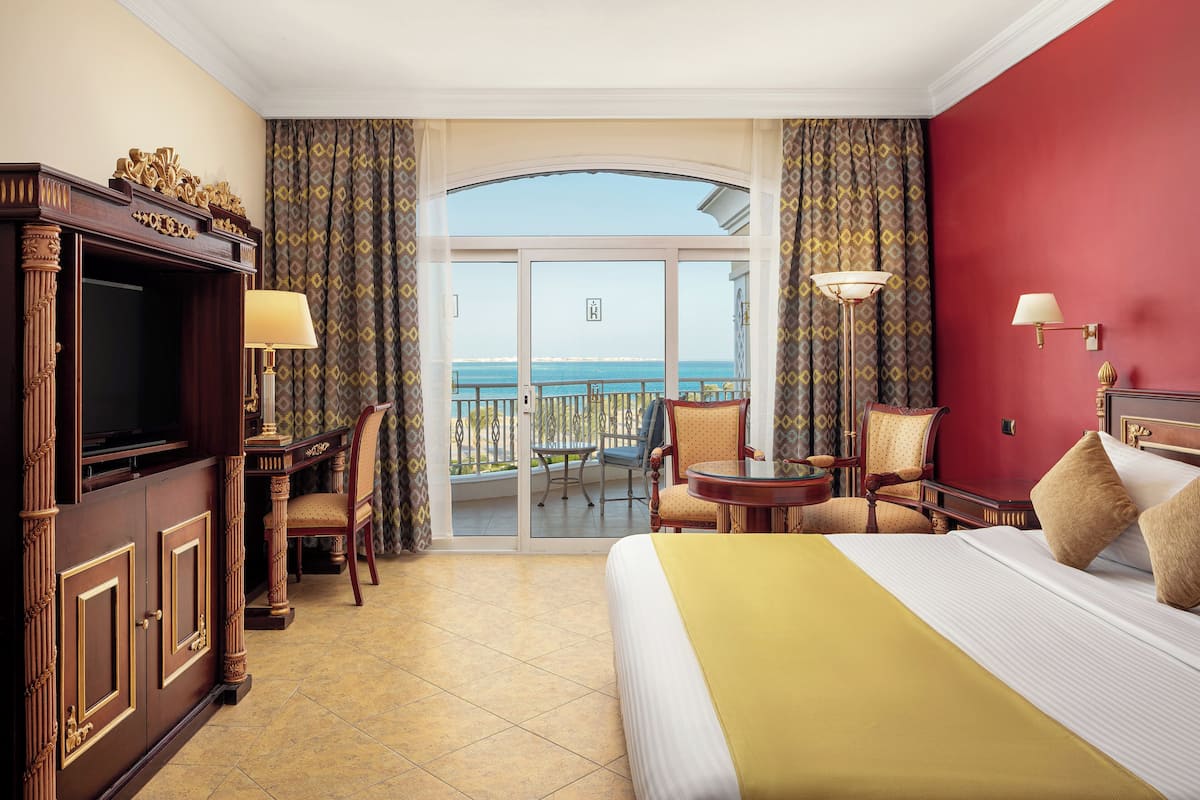 A hotel room with a balcony, a bed, a desk, and a television.