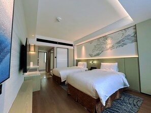 A hotel room with two beds, a flat-screen TV, a ceiling-mounted smoke detector, and a large abstract wall art piece.