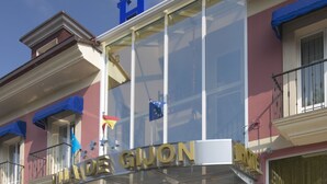 A hotel entrance with a glass facade, steps leading up to it, and a sign reading "VIADE GIUON". - Villa de Gijon (Gijon)