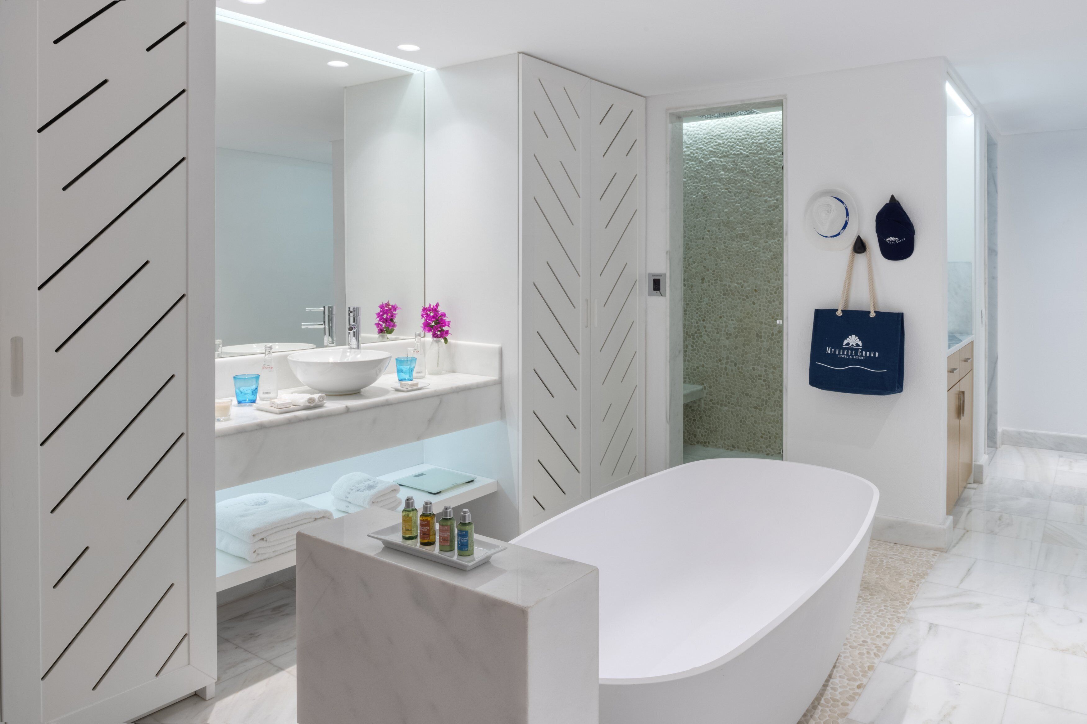 Un bagno moderno con una vasca freestanding, uno specchio grande, un mobile lavabo e un portasciugamani.