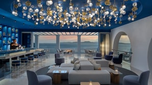 Un espace lounge moderne doté d’un bar, de si èges et offrant une vue sur la mer.