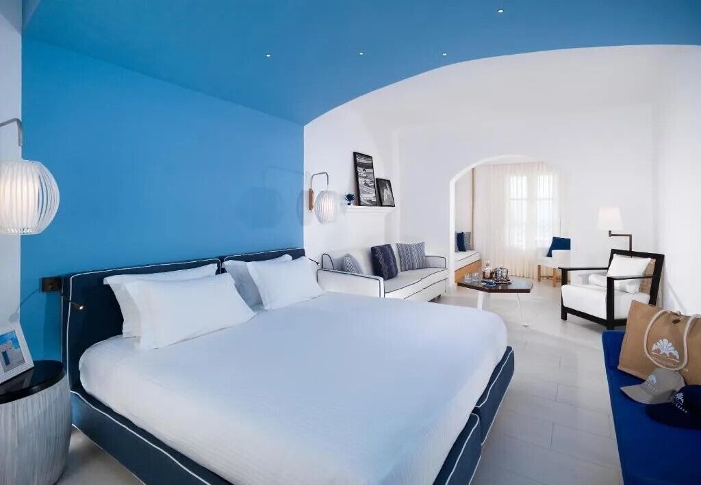 Une chambre d’hôtel avec un grand lit, un canapé, un bureau et une chaise.