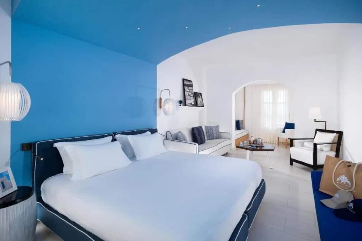 A hotel room with a large bed, a sofa, a desk, and a chair.