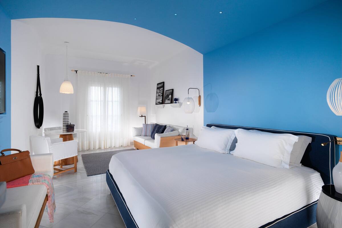 Een moderne hotelkamer met een groot bed, een bureau, een stoel en een bank.