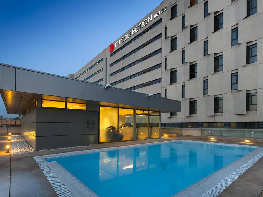 Un hotel moderno con piscina, ventanas amplias y un cartel llamativo.