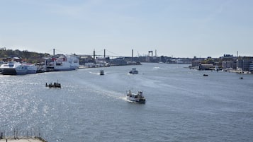 Een haven met meerdere boten, een brug en industriële gebouwen op de achtergrond.