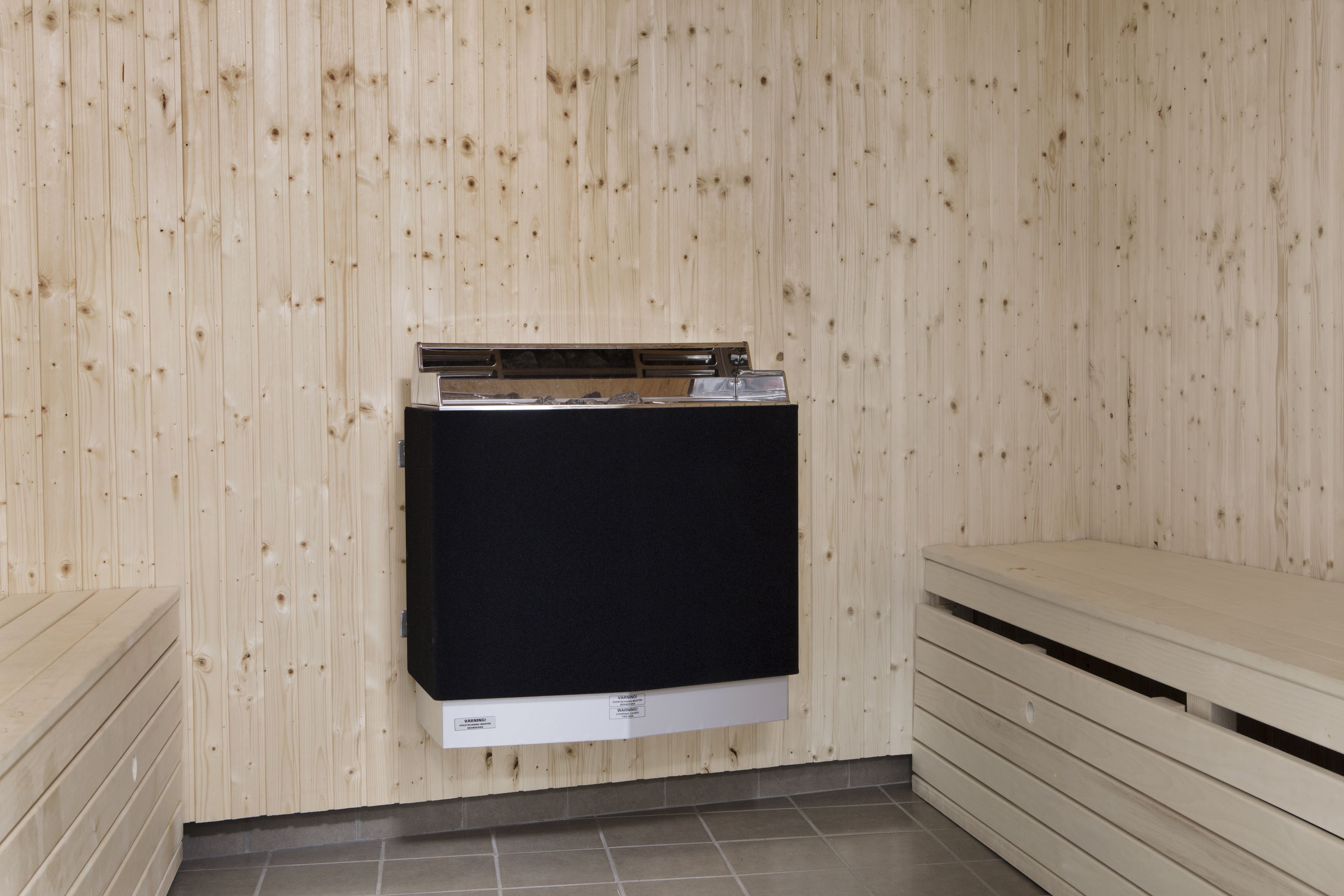 A sauna room with wooden walls, a black sauna bench, and a wooden bench on the right.