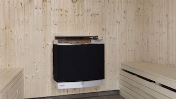 A sauna room with wooden walls, a black sauna bench, and a wooden bench on the right.