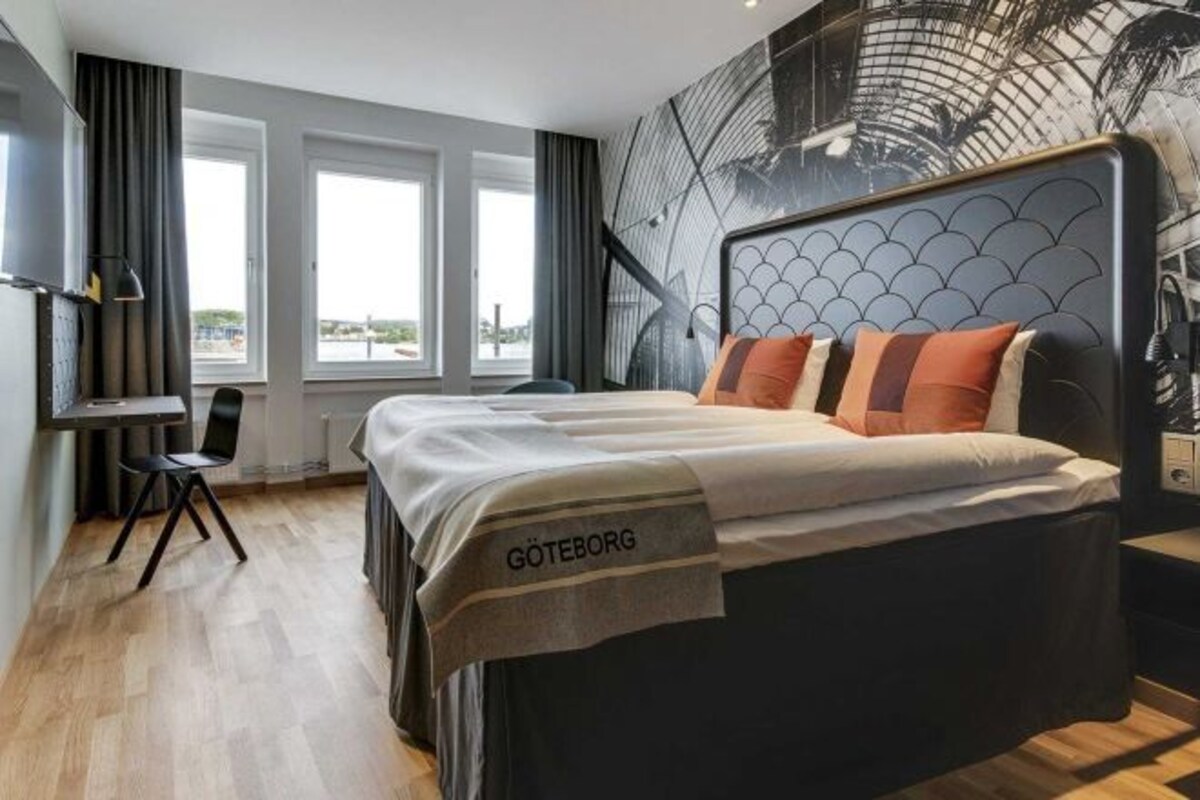 Una habitación de hotel con cama, escritorio y vistas a la ciudad.