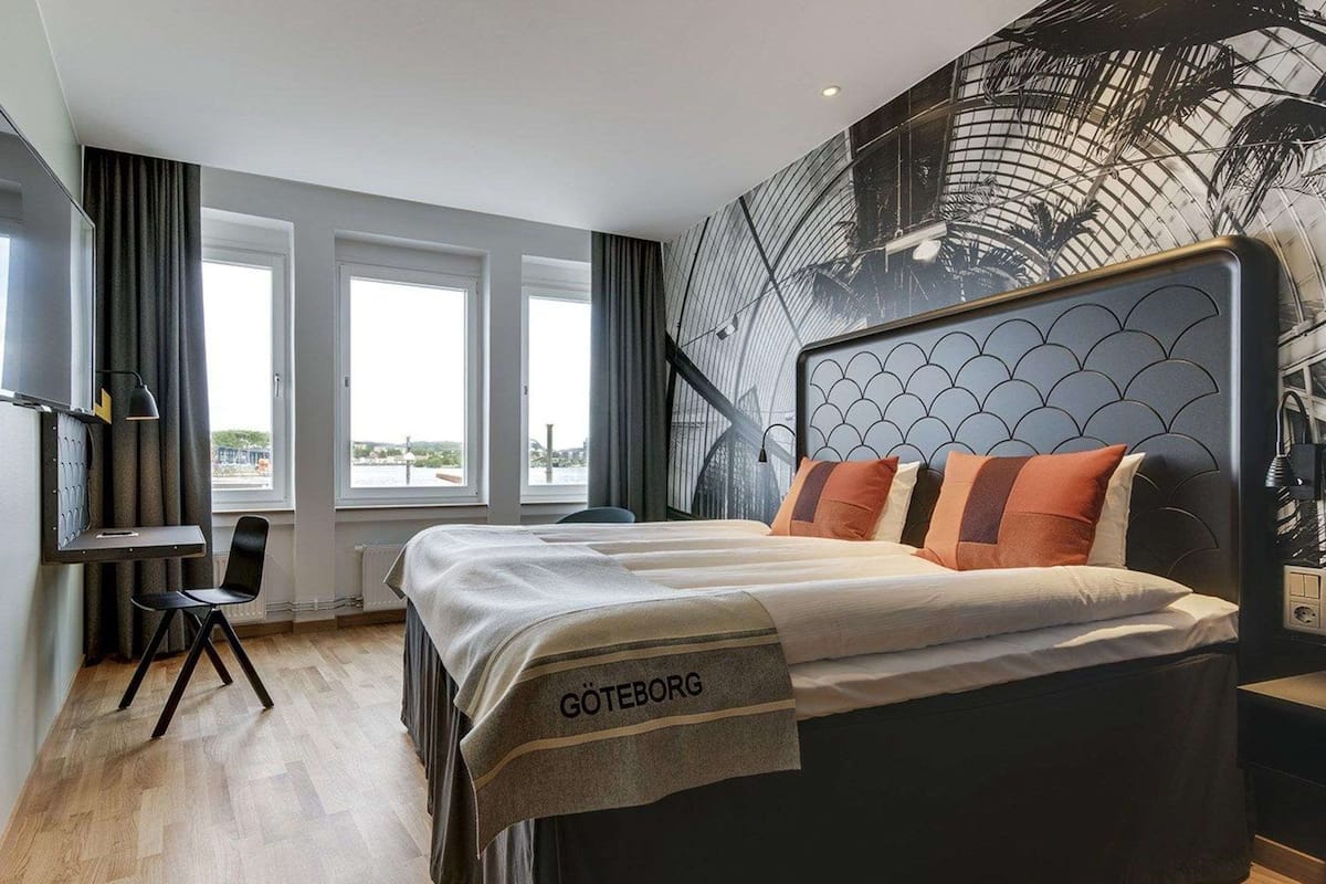 Una habitación de hotel moderna con una cama grande, un escritorio y vistas a la ciudad.