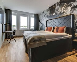 Una habitación de hotel moderna con una cama grande, un escritorio y vistas a la ciudad.