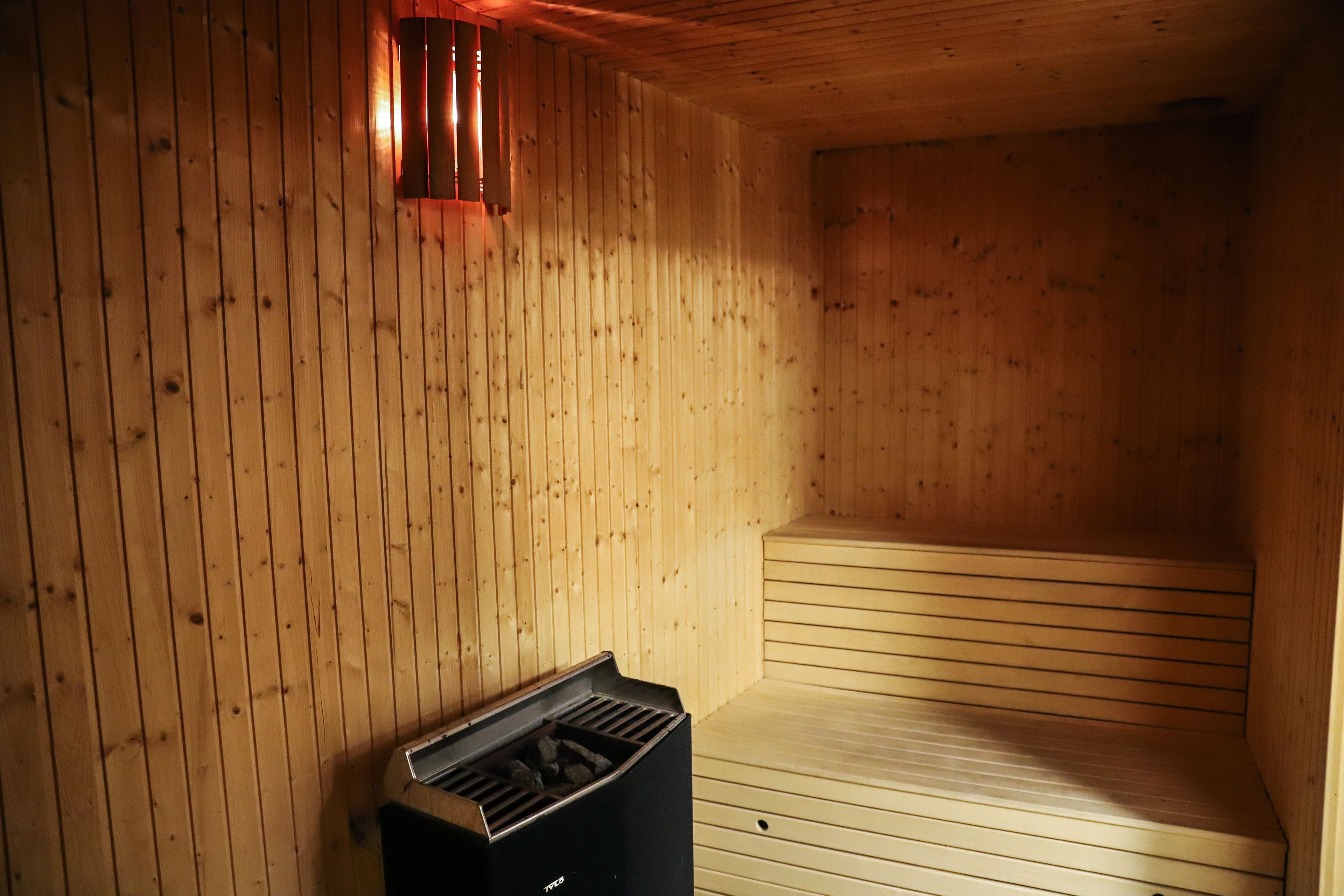 Un sauna avec des murs en bois et un banc.