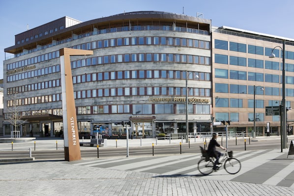 A modern hotel with a curved facade, multiple floors, and a prominent entrance.
