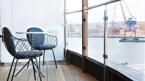A balcony with a view of a port and cranes, featuring two chairs and a table. - Comfort Hotel Goteborg (Gothenburg)