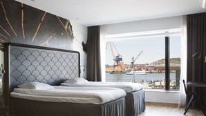 A modern hotel room with two beds, a large window with a view of a harbor, and a cityscape in the background. - Comfort Hotel Goteborg (Gothenburg)