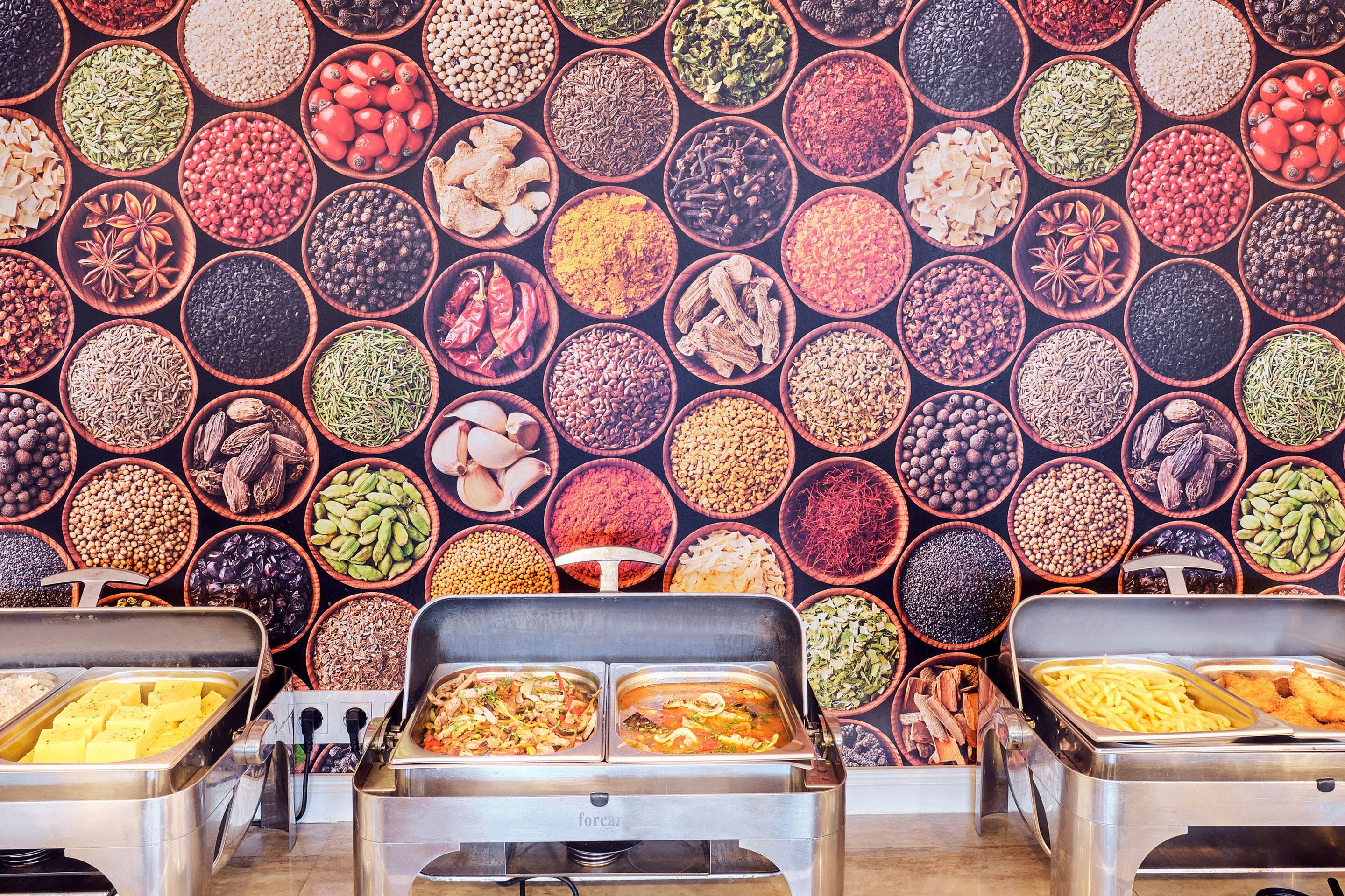 Un buffet proposant une variété de plats et un mur rempli d’épices.