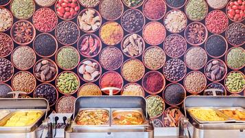 A buffet with various food items and a wall of spices.