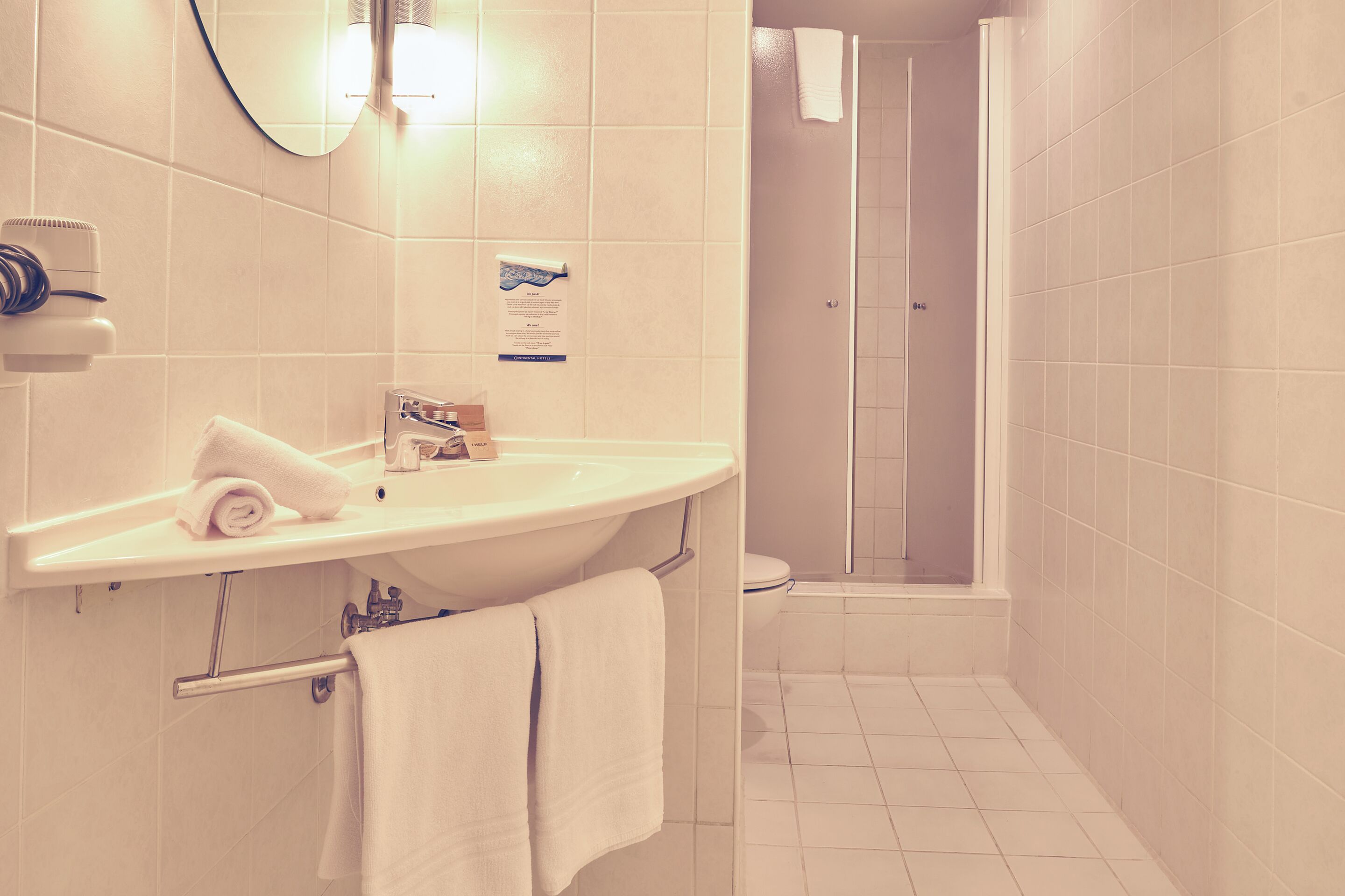 Un baño con lavamanos, espejo, toallero y zona de ducha.