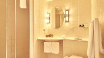 Un baño con ducha, inodoro, lavabo y espejo.