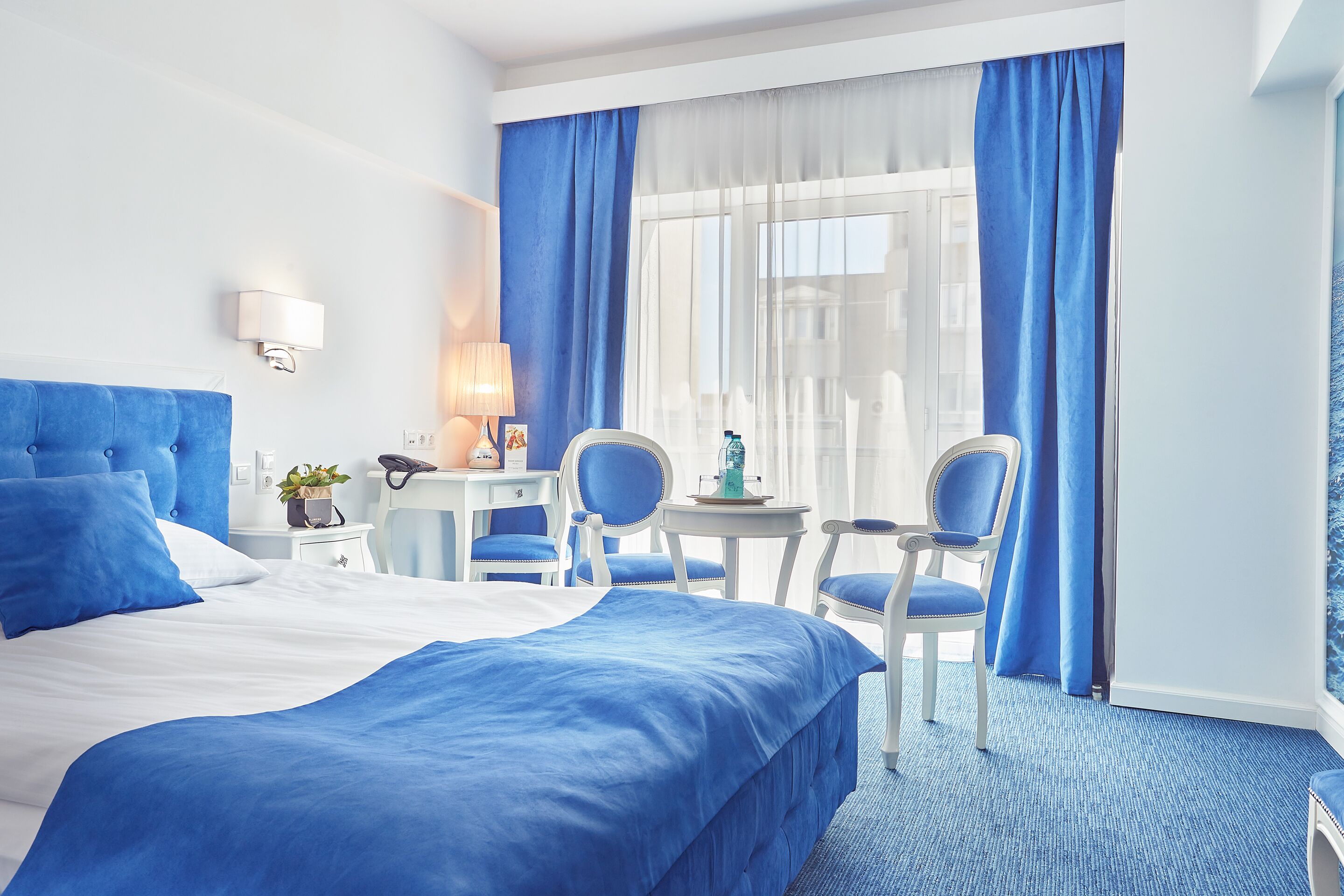 Ett hotellrum med en stor säng, två stolar, ett litet bord och ett skrivbord.