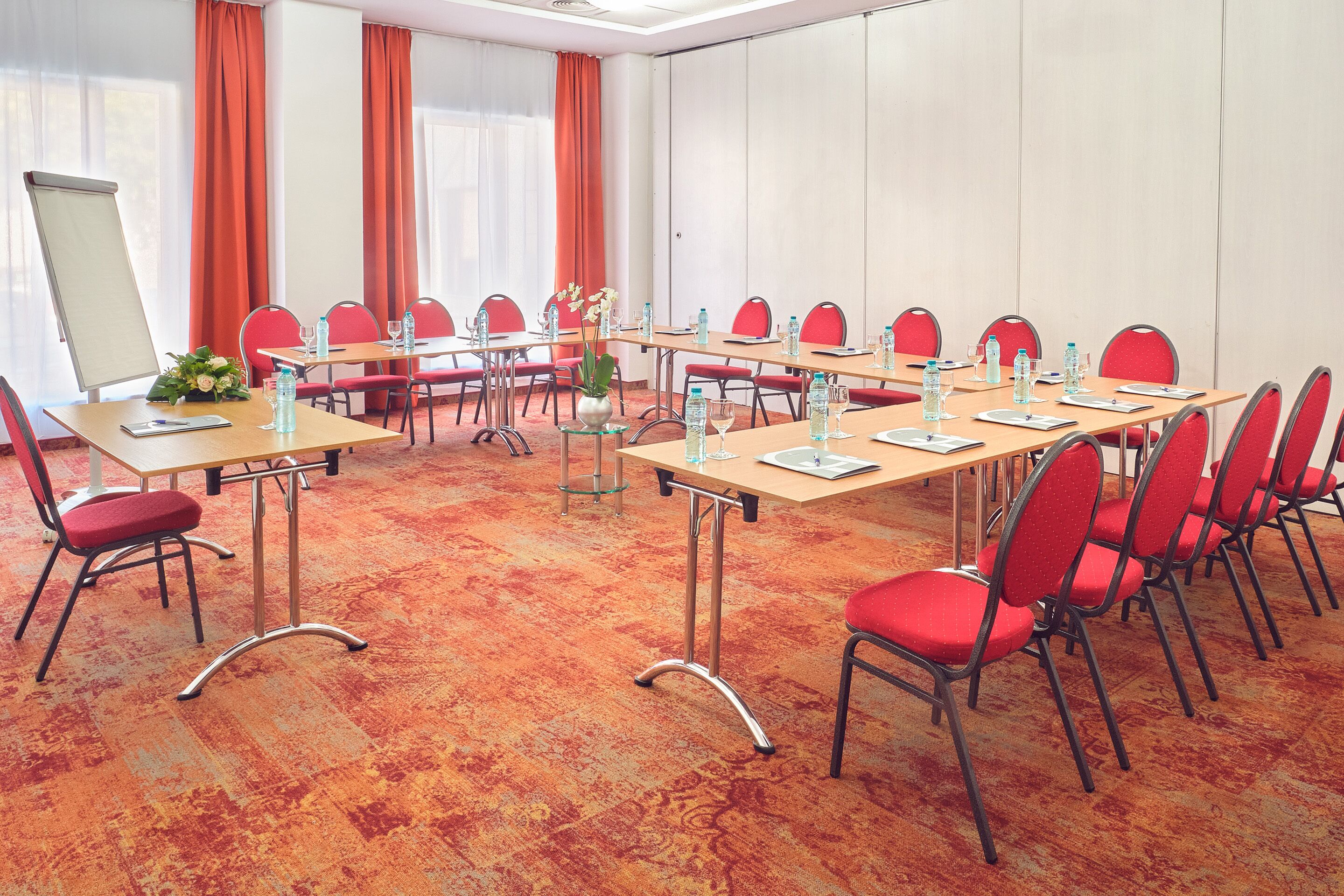 A conference room with a large table, red chairs, and a whiteboard.