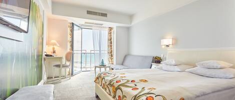 Habitación de hotel con cama, escritorio, silla, ventana con cortinas y vistas al exterior.