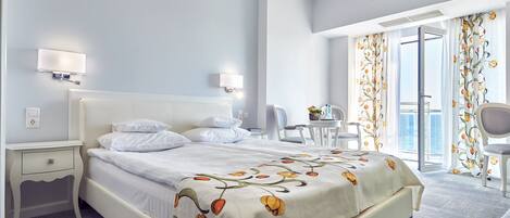 A hotel room with a bed, bedside tables, a desk, and a chair.
