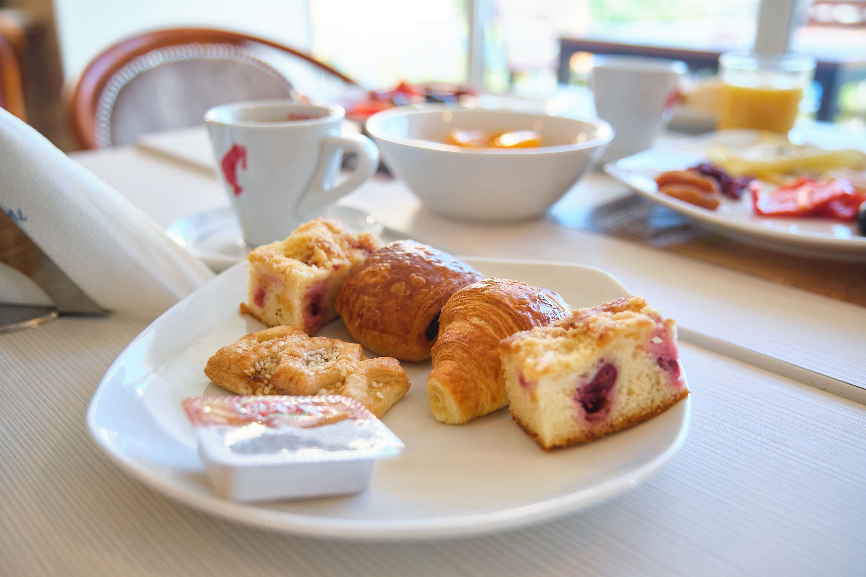 A breakfast setting with pastries, a croissant, and a cup of coffee on a table.
