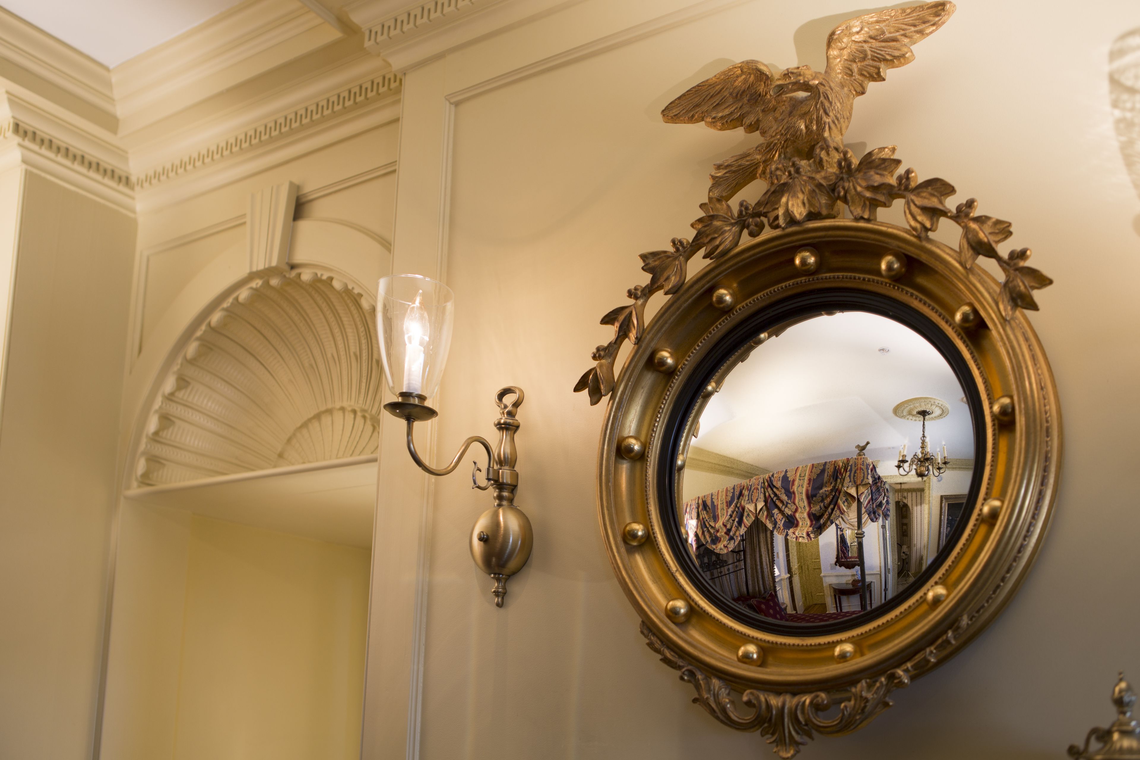 A wall-mounted ornate mirror with a gold frame and an eagle decoration.