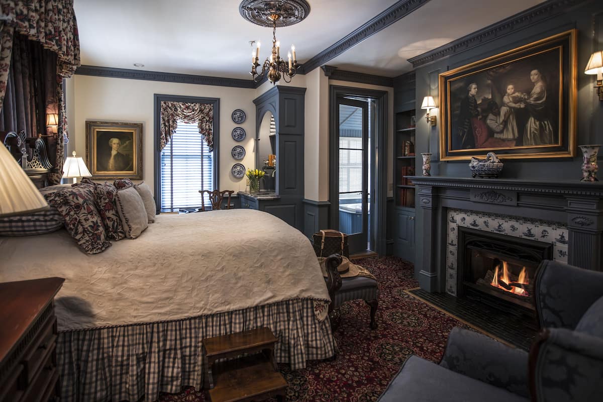 A traditional room with a large bed, a fireplace, and classic decor.
