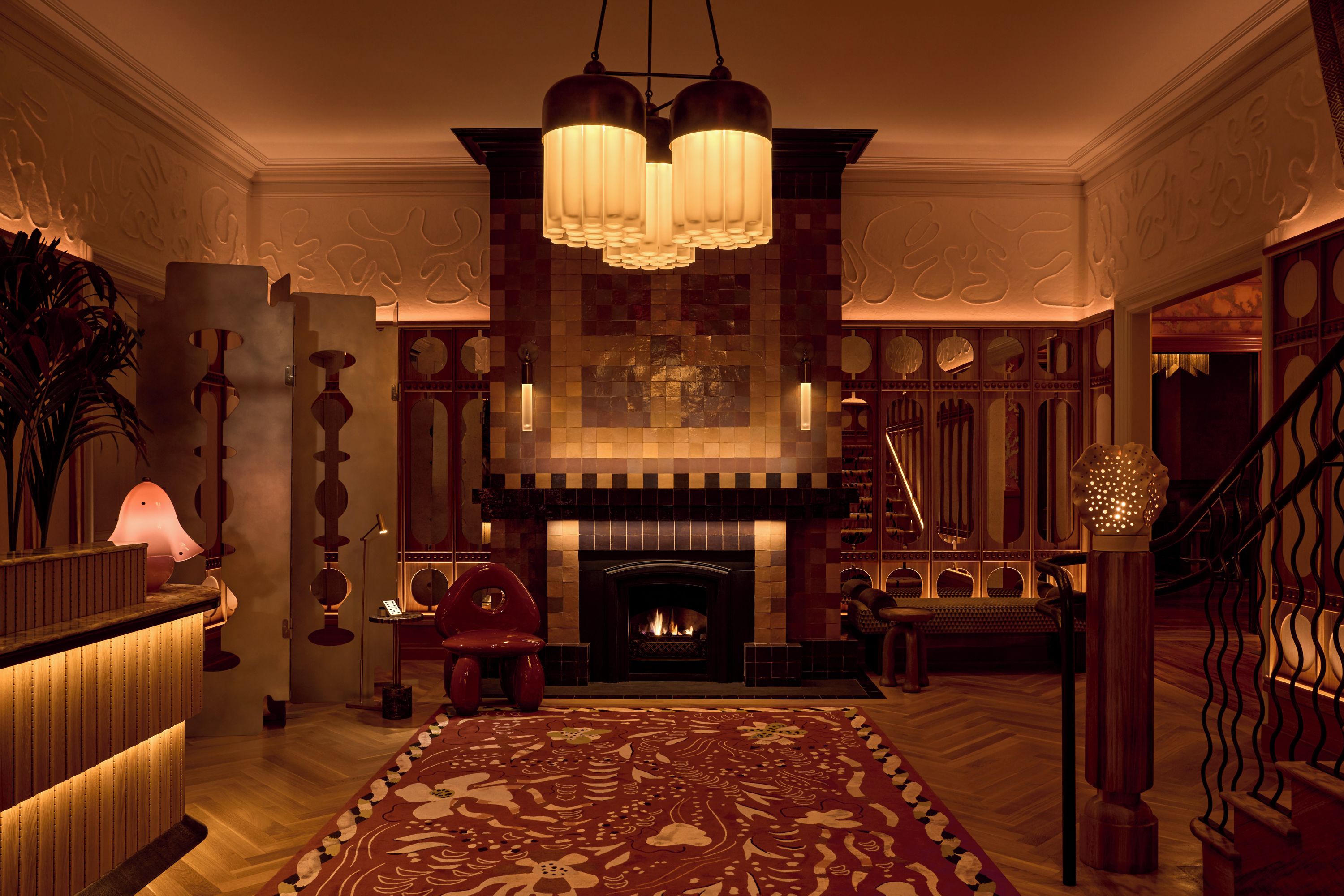 A grand lobby with a fireplace, a large ornate rug, and a staircase.