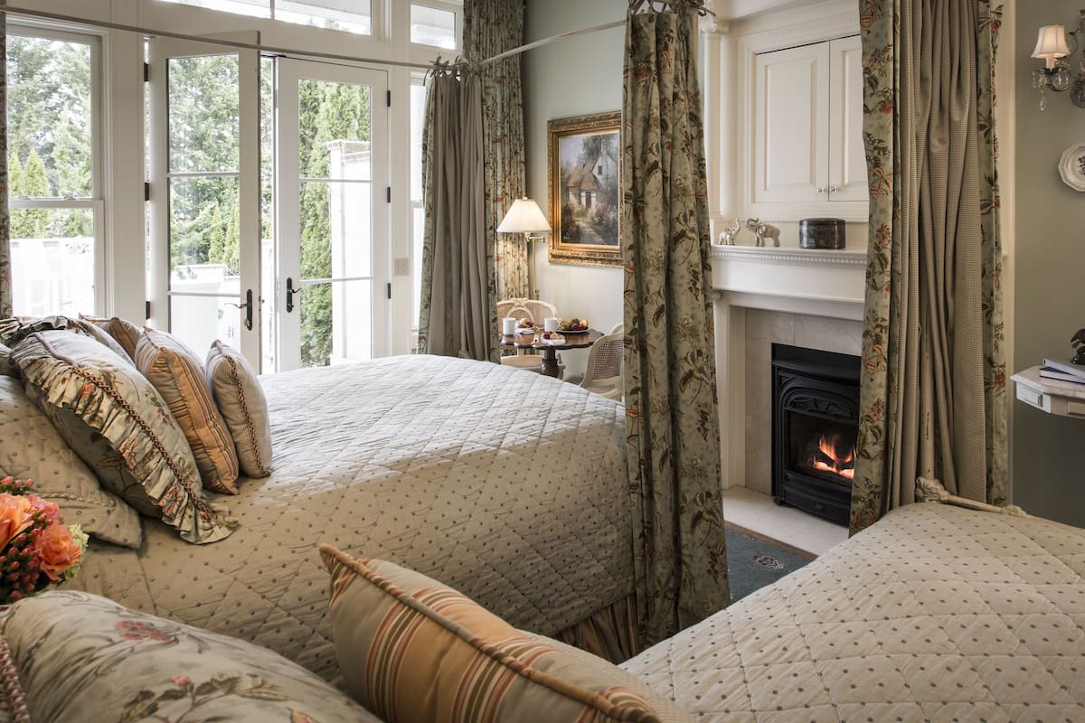 A bedroom with a large bed, a fireplace, and a view of the outdoors.