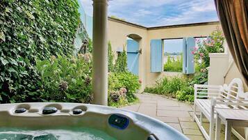 Un jacuzzi en un jardín con una pérgola, una mesa y sillas.
