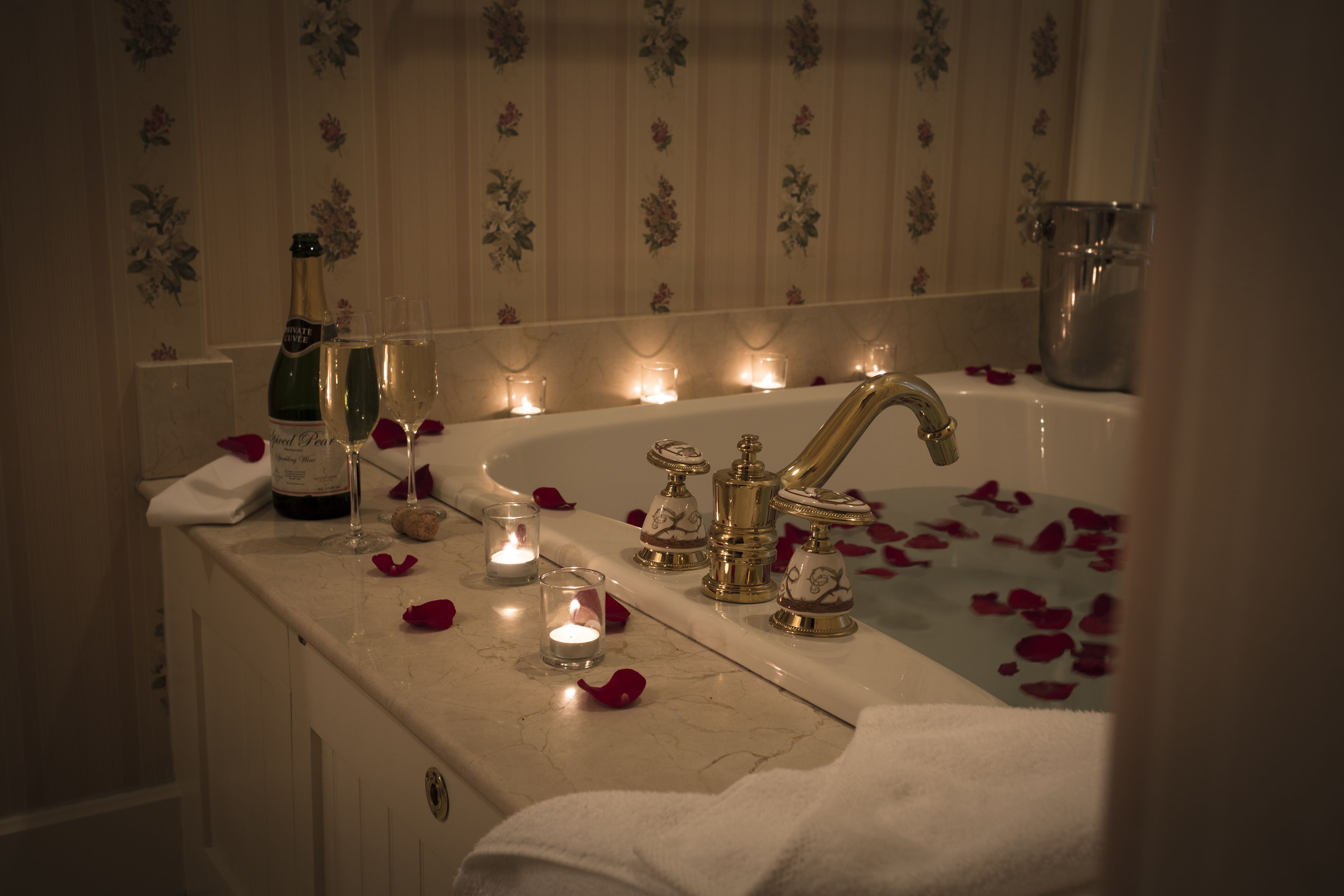 A bathroom with a bathtub, a sink, and a bottle of champagne.