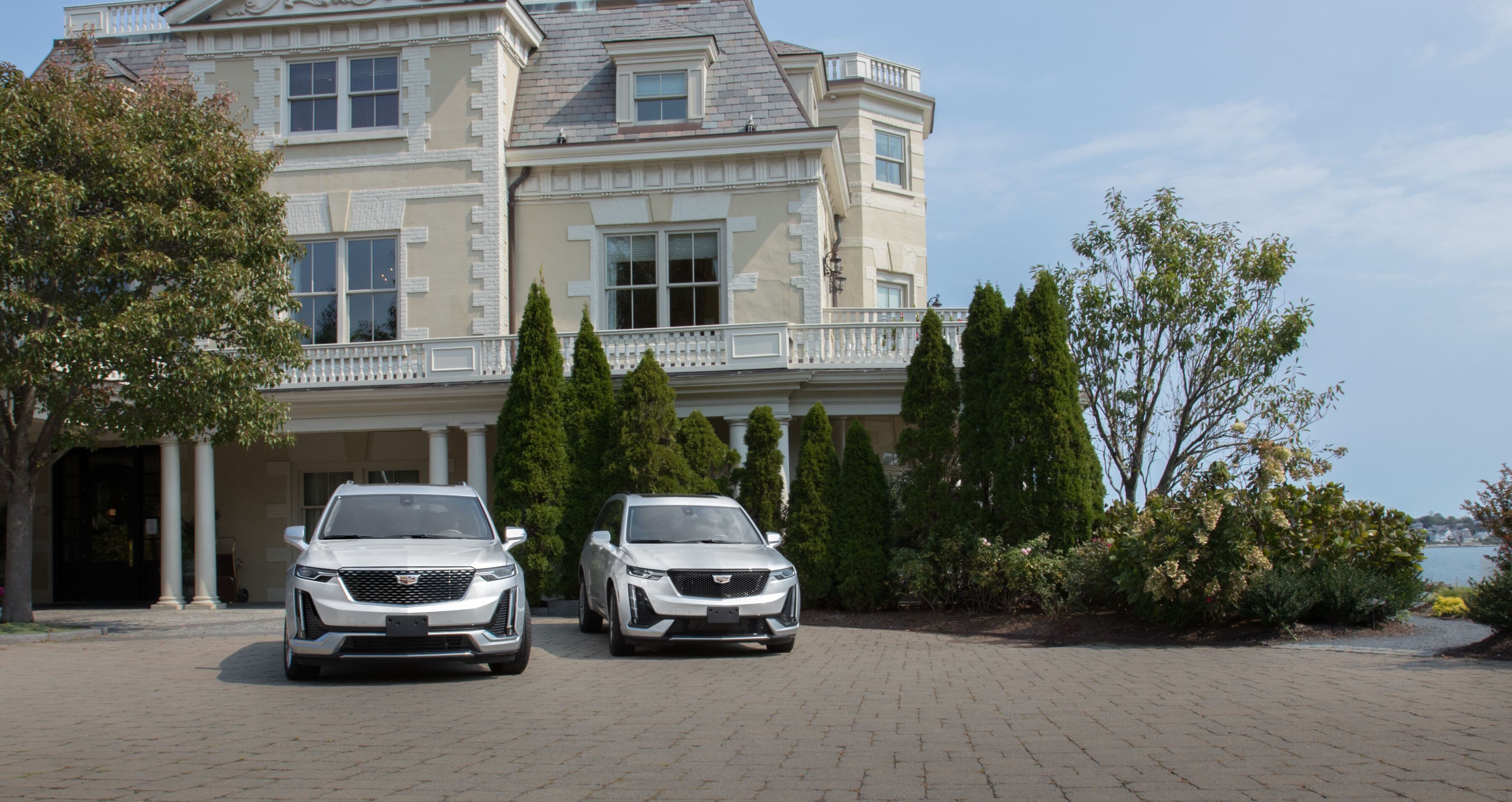 A large, stately building with two parked cars in front.