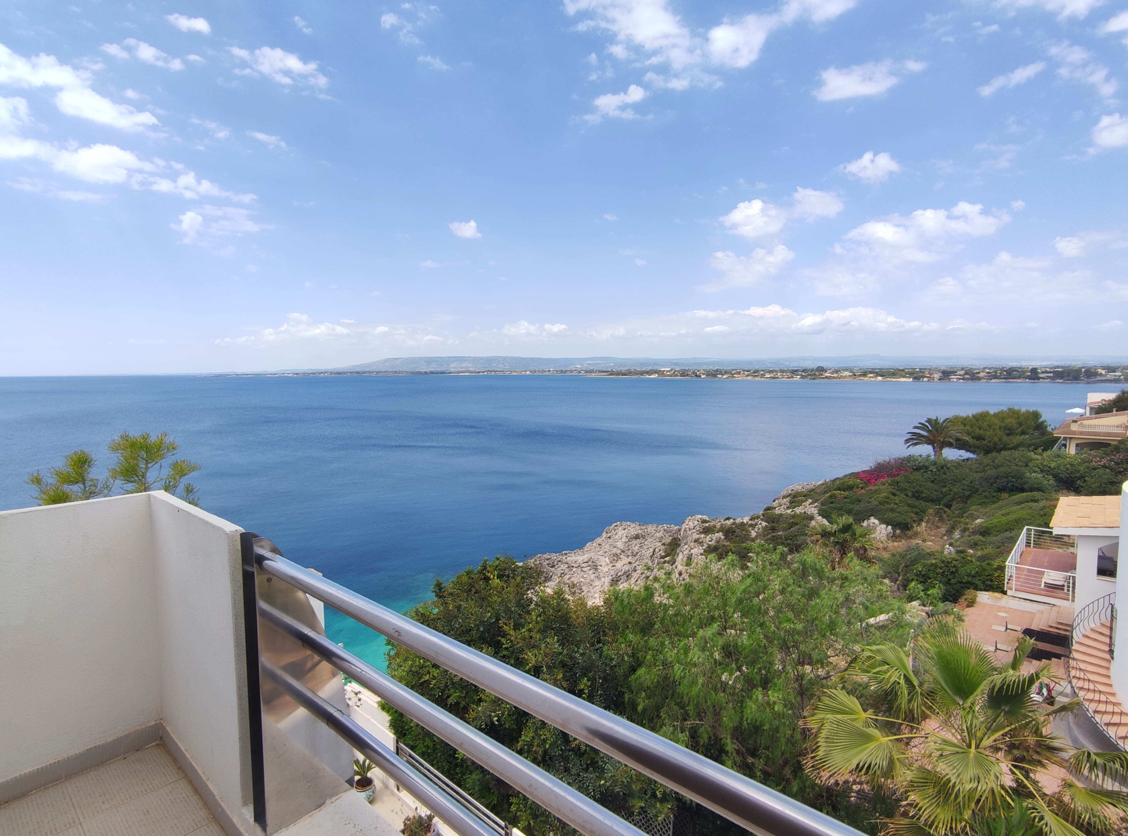 A balcony with a view of the sea and distant land.