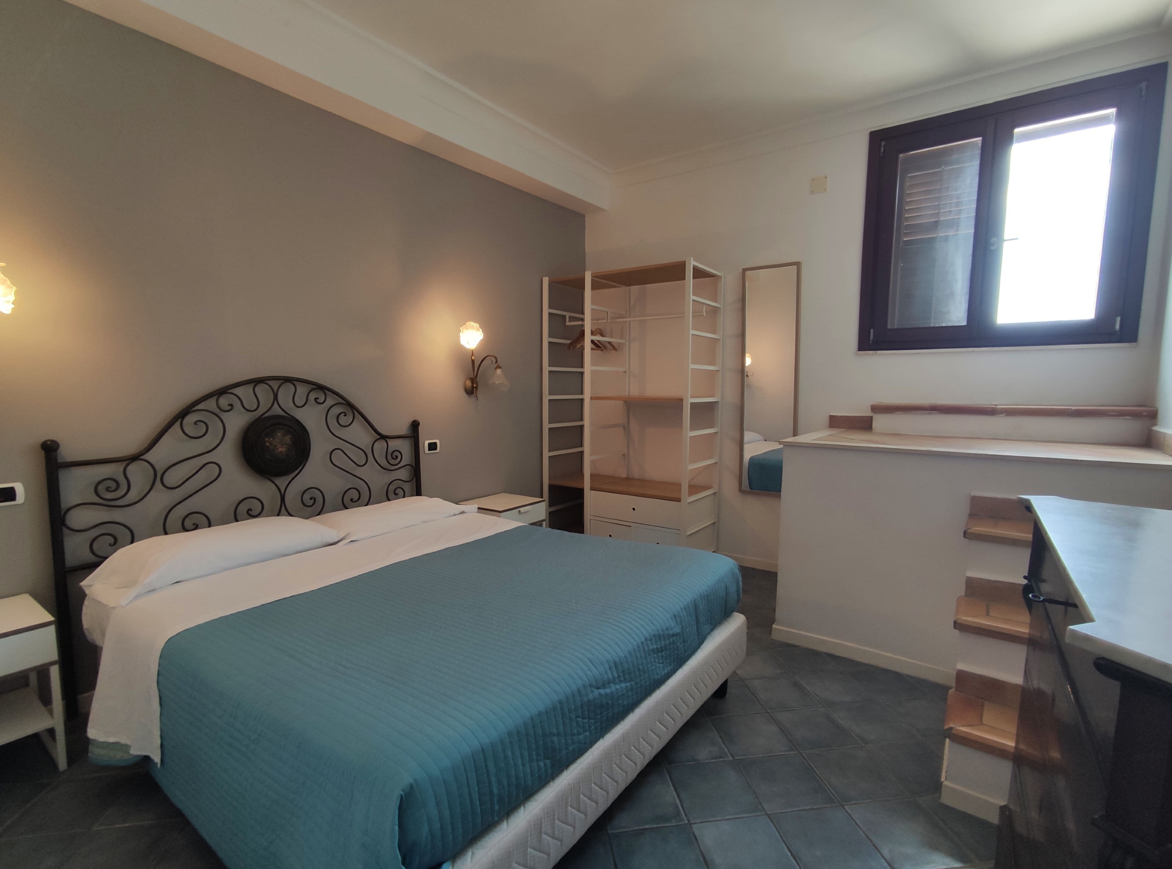 A bedroom with a bed, a wardrobe, a desk, and a window.