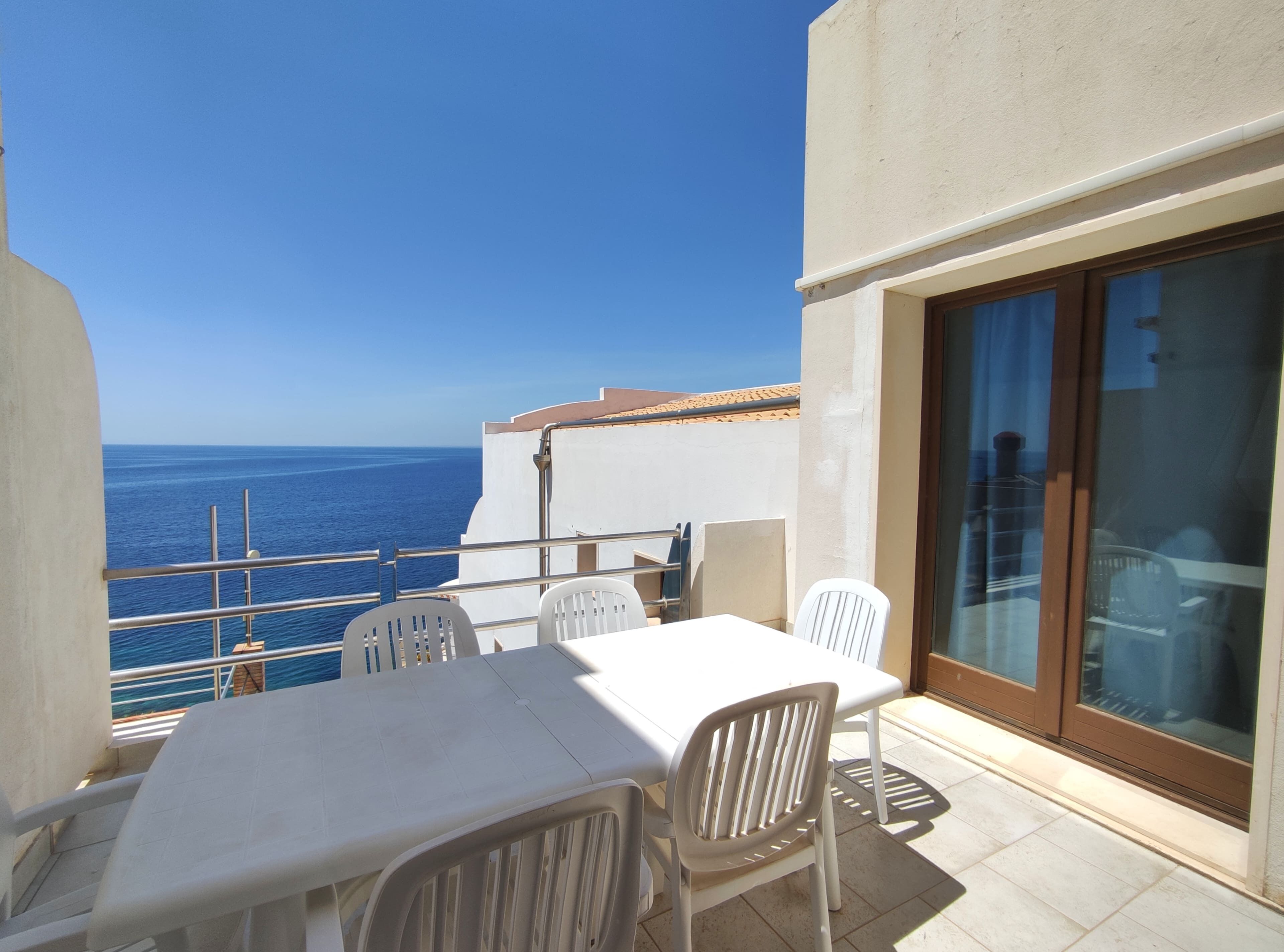 Un balcón con una mesa y sillas, con vistas al mar.