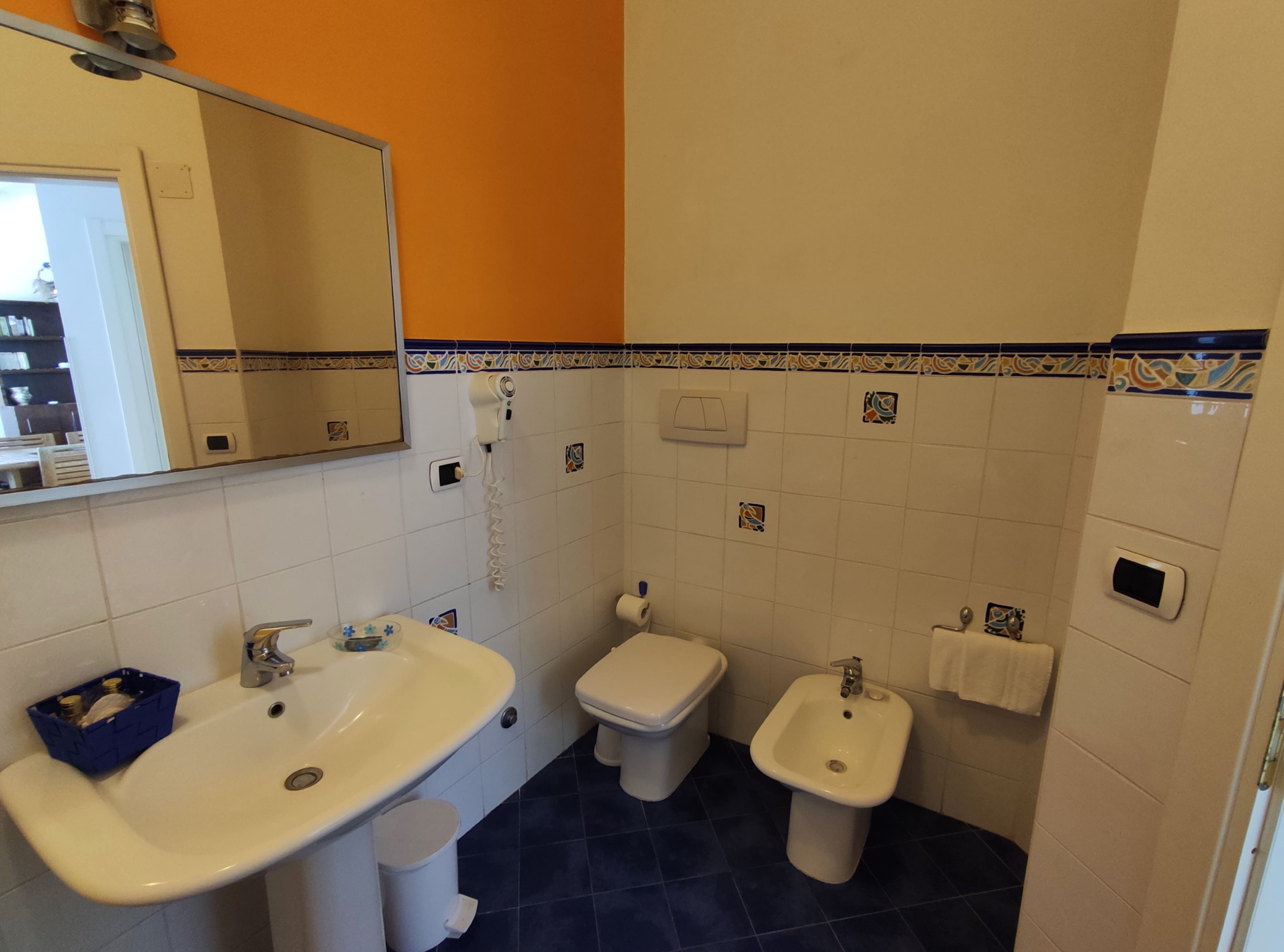 A bathroom with a sink, toilet, bidet, and a mirror.