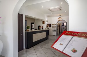 Un área de recepción de hotel moderna con mostrador, un atril para menús y una puerta visible.