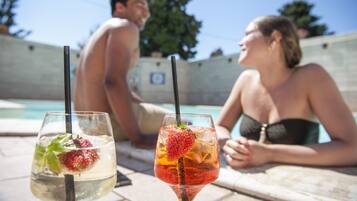 Dos cócteles con pajitas y adornos junto a una piscina.