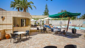 Una piscina al aire libre, sombrillas, sillones reclinables de piscina