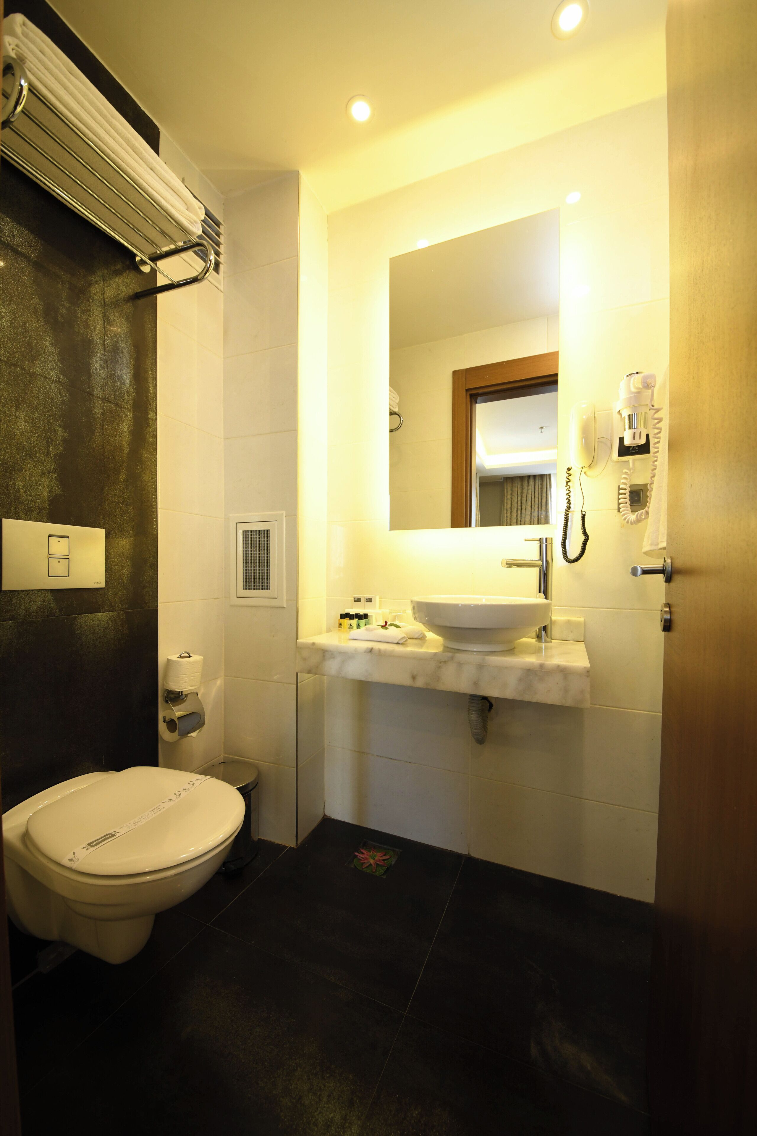 Une salle de bain comprenant des toilettes, un lavabo, un miroir et un espace douche.