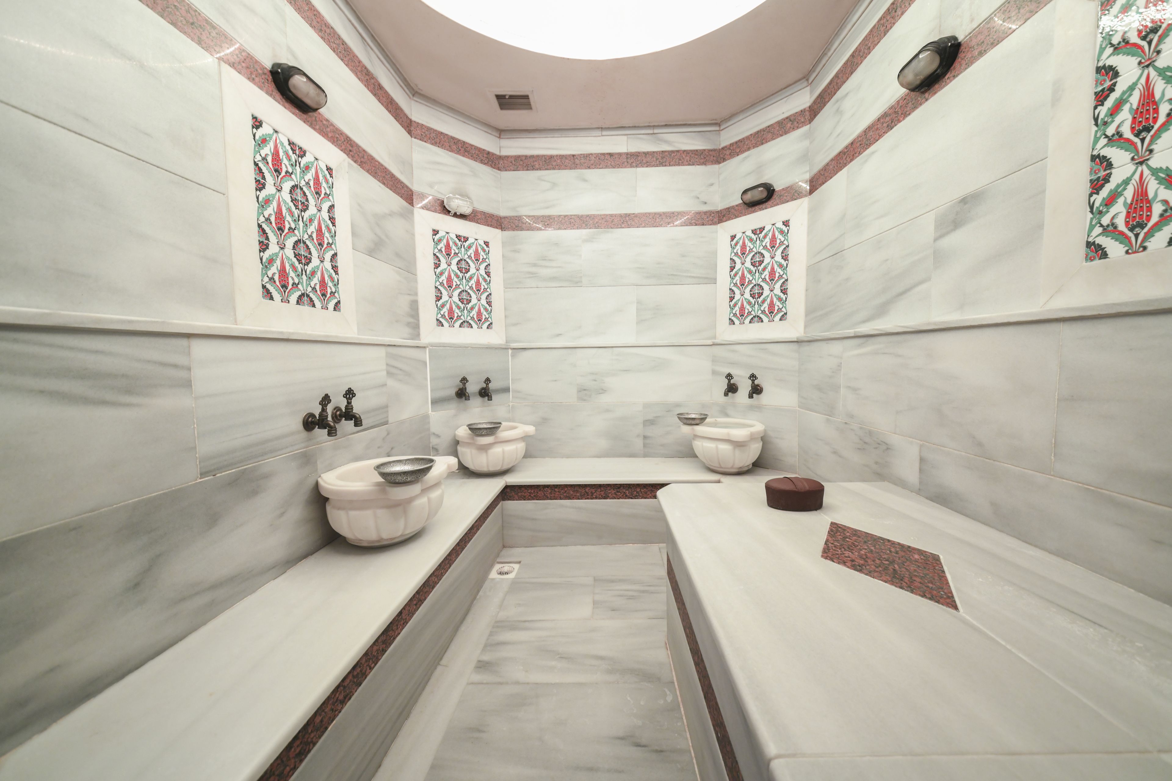 A modern bathroom with marble walls, a central sink, and decorative tiles.