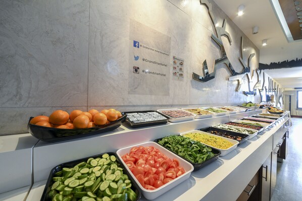 Un buffet proposant une variété de plats, notamment des fruits, des légumes et des salades.