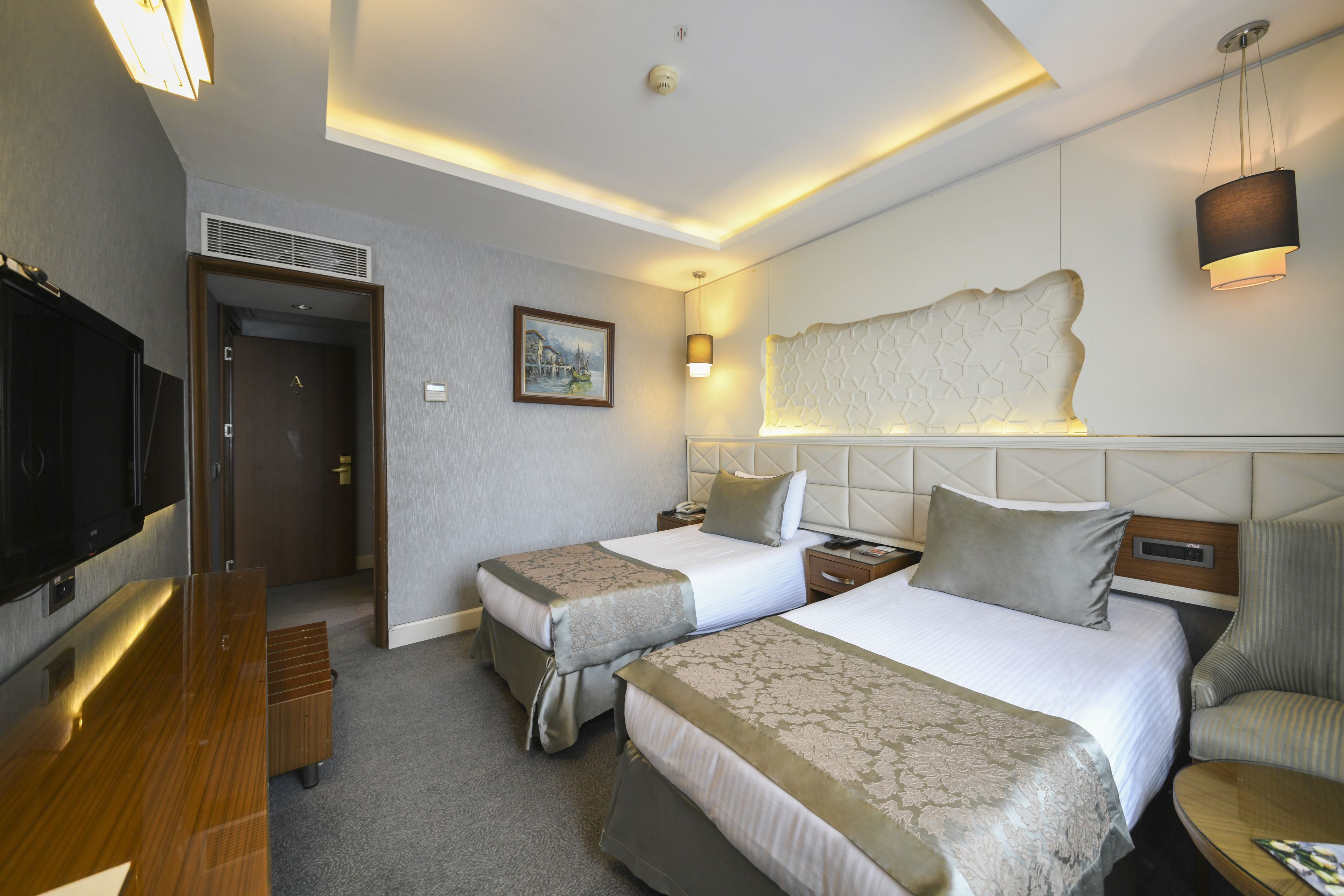 A hotel room with two beds, a TV, a desk, and a chair.