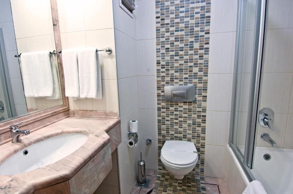 A bathroom with a marble sink, a toilet, and a shower area.