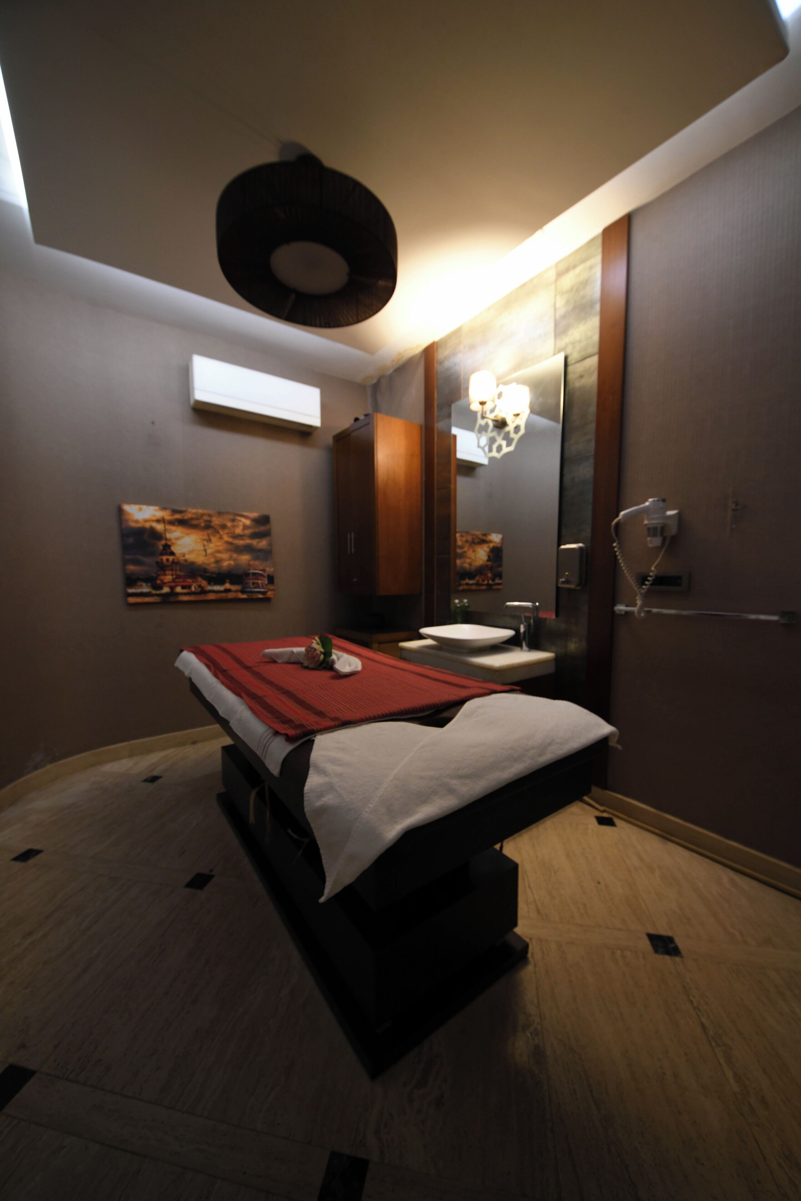 A modern hotel room with a bed, a bedside table, a large mirror, a sink, and a toilet.