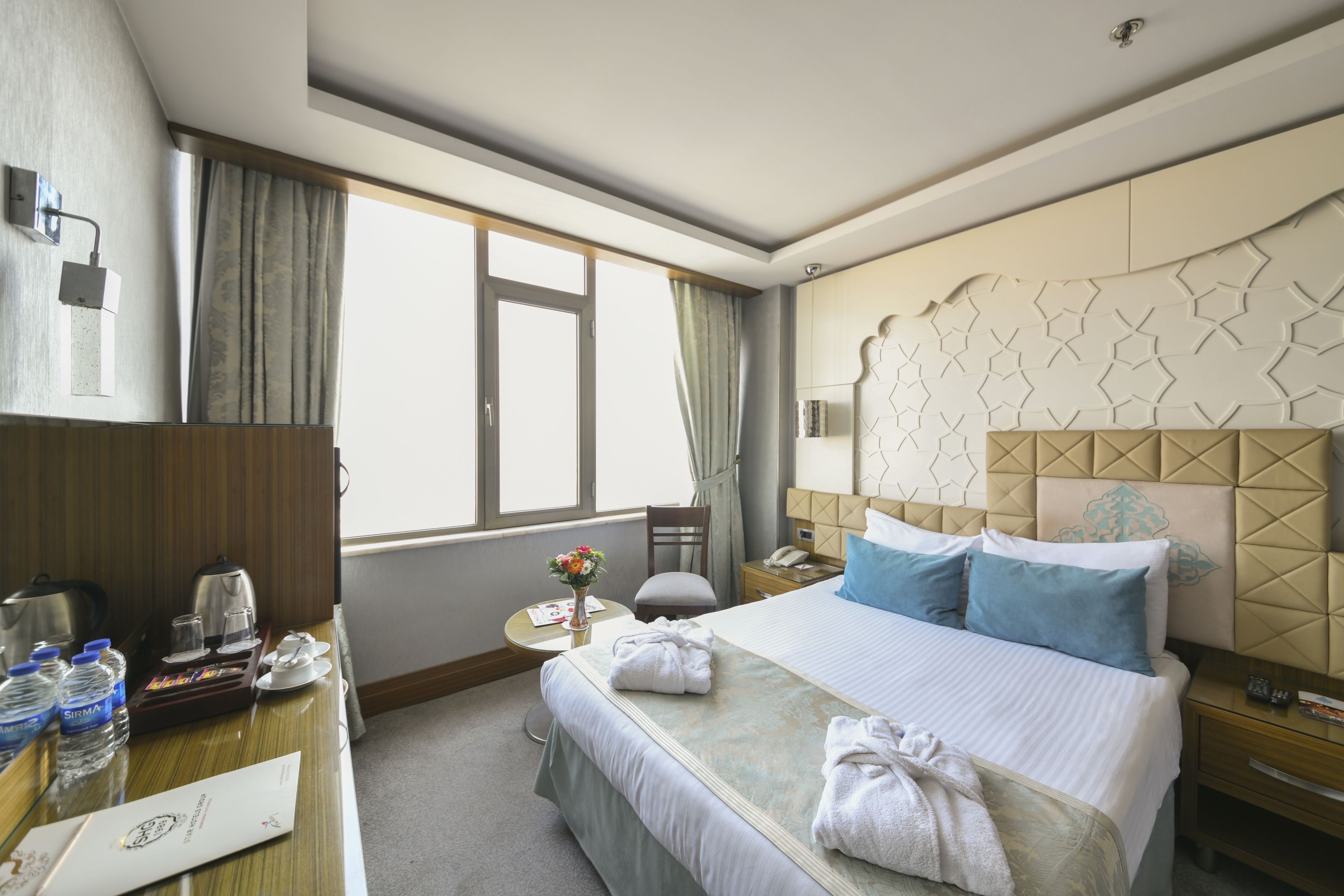 A hotel room with a bed, bedside table, and a desk with a chair.