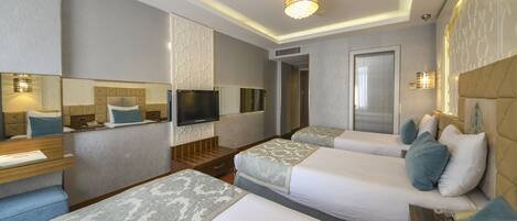 Habitación de hotel con dos camas, un televisor, un espejo y un escritorio pequeño con una lámpara.